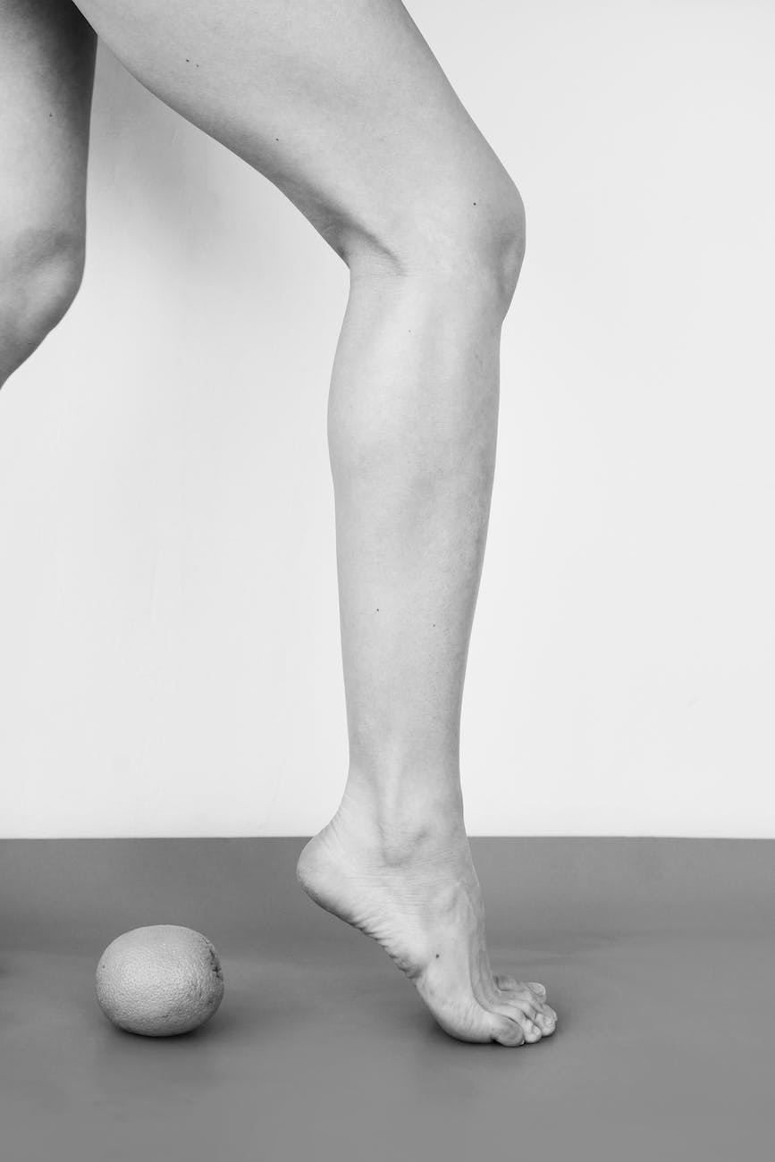 grayscale image of female legs and a fruit
